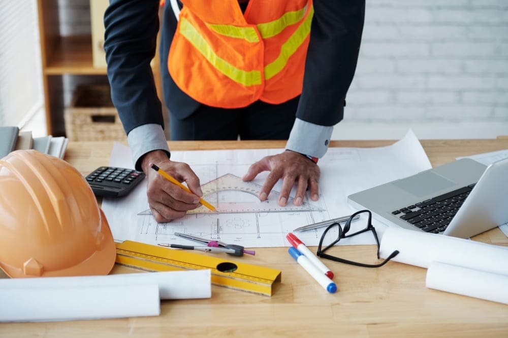 Casque de chantier posé sur des plans : RC pro et décennale de l'artisan du BTP